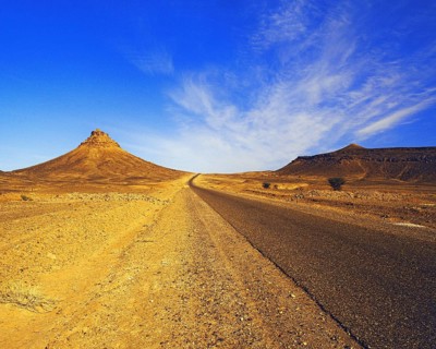 Lonely road penetrating sandy rocky hills in the eastern Atlas Mountains, southern Morocco