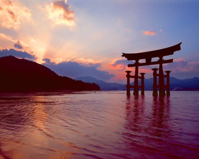 The bright red Sea-gate of Miyajima temple, Japan, against a background of sea and the low hills