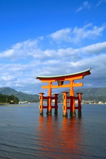 The bright red Sea-gate of Miyajima temple, Japan, against a background of sea and the low hills
