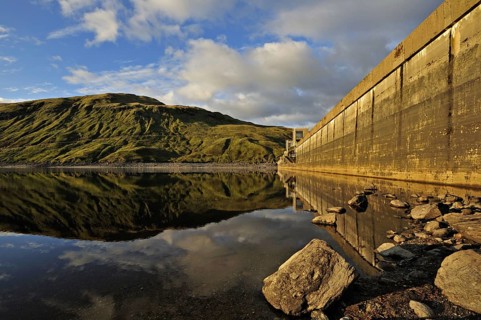 Hydro-electric dam and reservoir in Glen Lyon with pebbled shore and distant ridgeline, Glen Lyon,