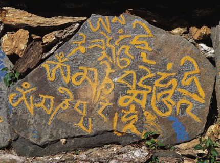 Carved mane-stone carrying the Buddhist message Om mane Padme hom by the side of a trail in east