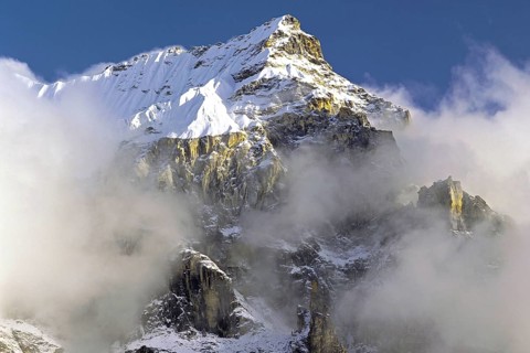 Afternoon mist and clouds gather around the dramatic crags and summit of an un-named peak in the