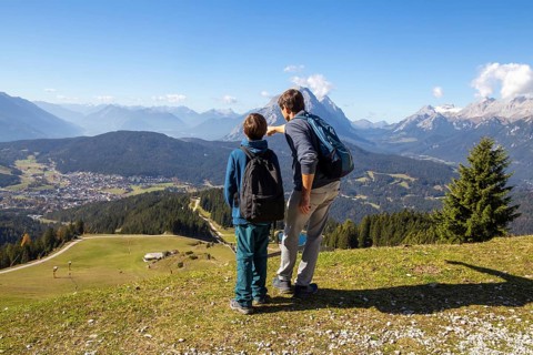 Hiking with children in Seefeld, Tyrol: Father shows his son the landscape. The snow-covered peak