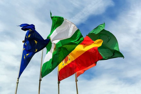 Four flags next to each other, fluttering in the wind, strong wind, European Union, Andalusia,