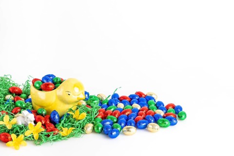 Chocolate eggs and a decorative chick surrounded by artificial grass as a festive decoration, white