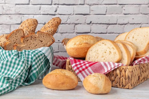 Fresh pastries and bread in two baskets in front of a brick wall