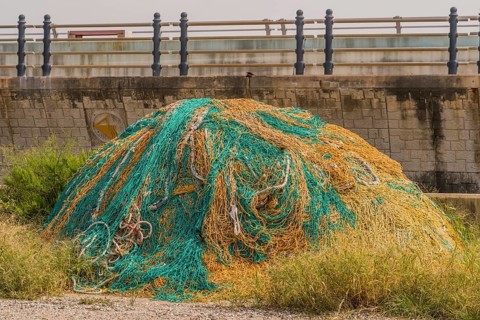 Large ball of yellow and green fishing nets in front of sea wall on cloudy day in South Korea