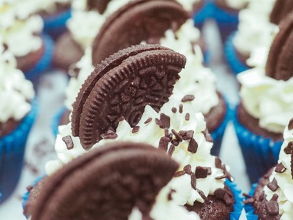Close-up of a large group chocolate cupcakes with white cream frosting, dark chocolate cookie