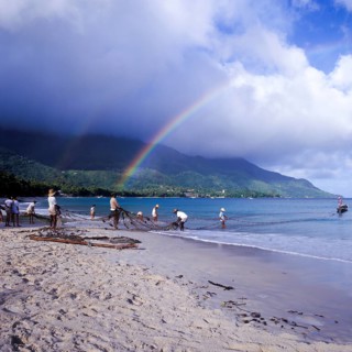 Seychelles, Mahe, Beau Vallon, fishermen pull fishing net ashore, Africa