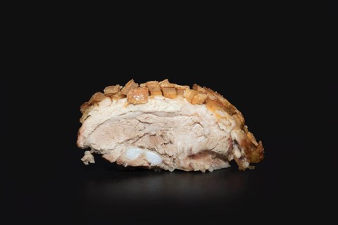 A sliced, freshly roasted pork belly with a crispy crust, food photography with a black background