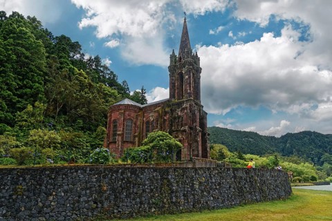 Old gothic church Capela de Nossa Senhora das Vitorias surrounded by trees and a stone wall against