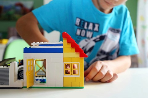 Boy builds a house with building blocks