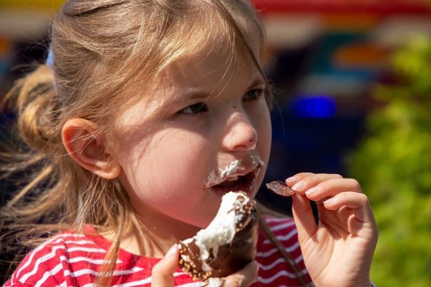 Seven-year-old girl eats a chocolate kiss at a folk festival