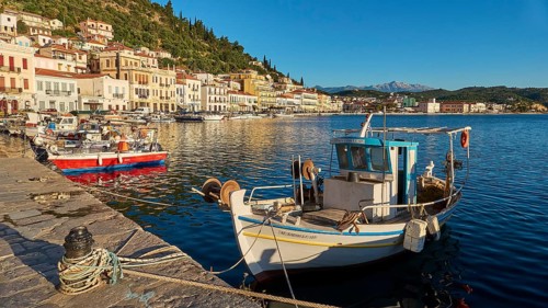 Quiet harbour with boats in front of picturesque coastal town and mountains in the background,
