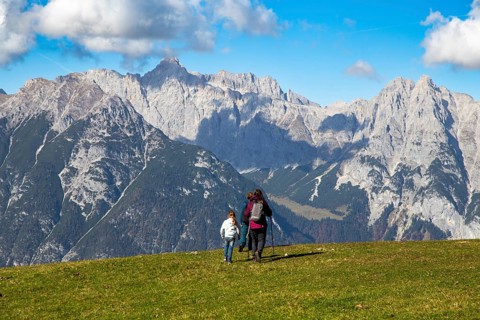 Hiking with children in Seefeld, Tyrol: Family hiking across an alpine meadow, with the Wetterstein