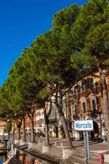 Old Beautiful Town with Building and Trees on the Waterfront on Lake Lugano with Boat in a Sunny