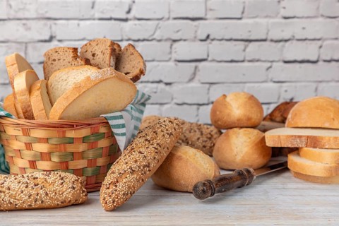 Various wholemeal and white breads in a bread basket on a country-style worktop
