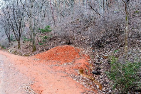 Mound of red clay next to hiking trail in mountainous recreational forest