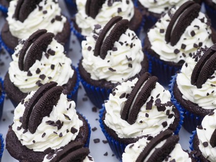 Production of A group of unhealthy dark chocolate cupcakes with sweet frosting cream and cookie