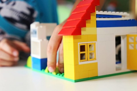 Boy builds a house with building blocks