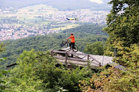 Mountain biker stands on the launch ramp for hang-gliders below the Melibokus and looks out over