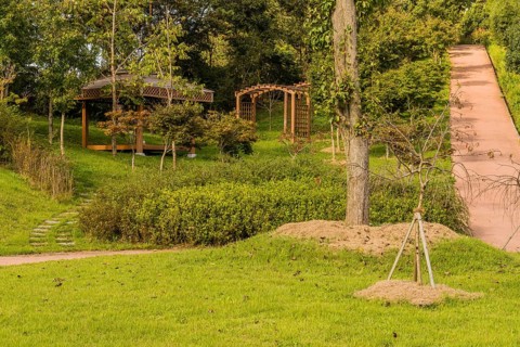 Landscape of urban park with covered gazebo, wooden trellises and concrete hiking trail in South