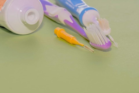 Closeup of toothbrushes and flossing picks next to opened tube of toothpaste
