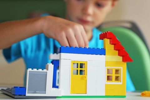 Boy builds a house with building blocks