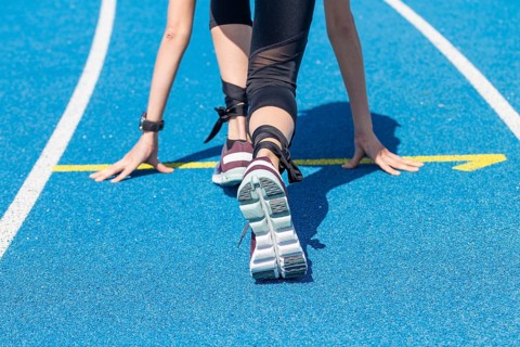 Athletics symbol: Young woman in front of the start of a race