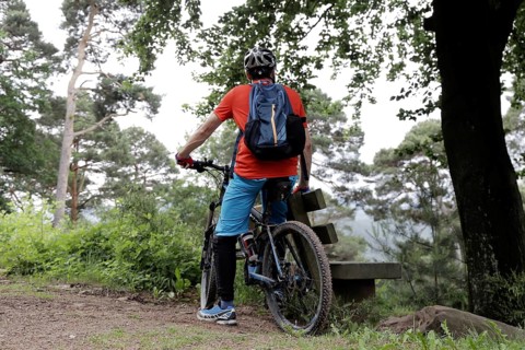 Mountain biker taking a break on a bench in the Palatinate Forest near the Weinbiet above Neustadt