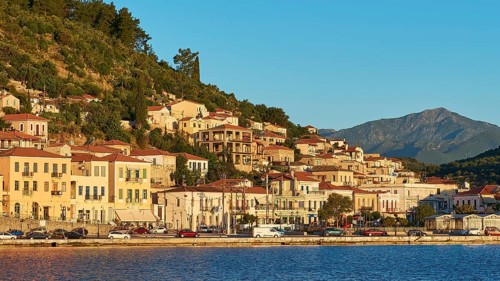 Traditional houses on a hill adjacent to calm waters in the morning light, Taygetos Mountains,