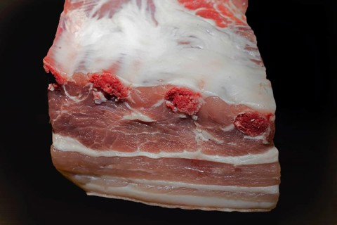 A piece of lean belly meat with bone, food photography with black background