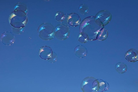 Soap bubbles multicoloured film of soapy water next to each other in front of a blue sky