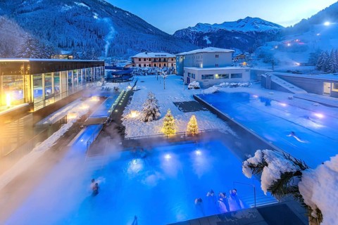 Snow-covered rock spa in winter, thermal bath with Christmas lights at dusk, Bad Gastein, Gastein