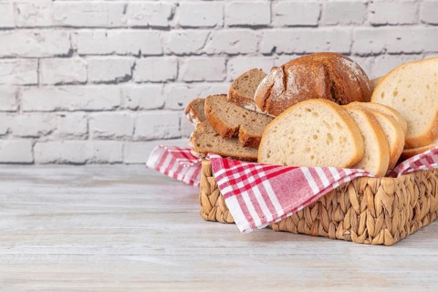 A basket with different types of bread on a brick wall, copy room