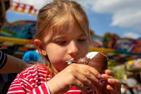 Seven-year-old girl eats a chocolate kiss at a folk festival
