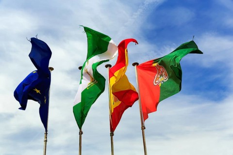 Four flags next to each other, fluttering in the wind, strong wind, European Union, Andalusia,