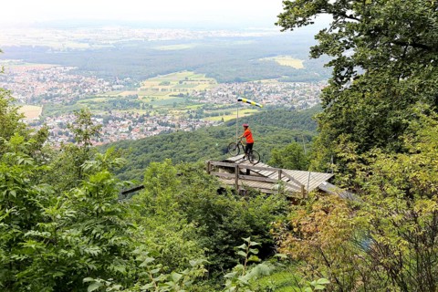 Mountain biker stands on the launch ramp for hang-gliders below the Melibokus and looks out over