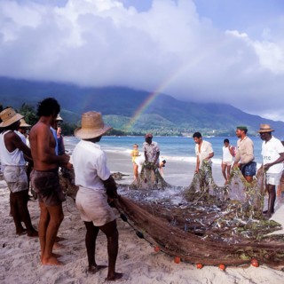 Seychelles, Mahe, Beau Vallon, fishermen pull fishing net ashore, Africa