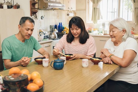 Japanese adult family eating rice with chopsticks. White-haired elderly mother enjoys watching her