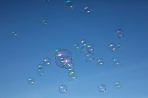 Soap bubbles multicoloured film of soapy water next to each other in front of a blue sky