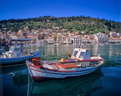 Small boats in the calm harbour water with mountain and city view in the background, Gythio, Mani,