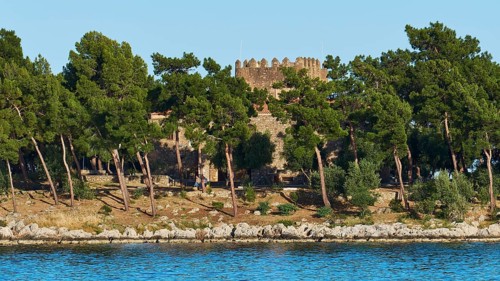 Old stone castle surrounded by pine trees on the Mediterranean coast, Gythio, Mani, Peloponnese,
