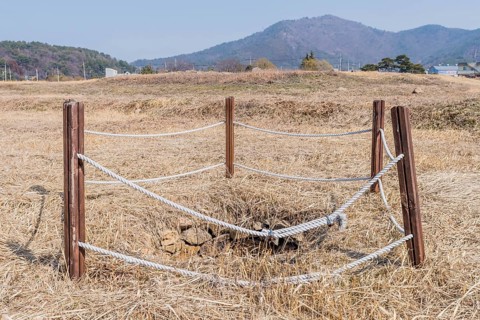 Water well cordoned off with wooden beams and rope at remains of stone fortress in Yeosu, South