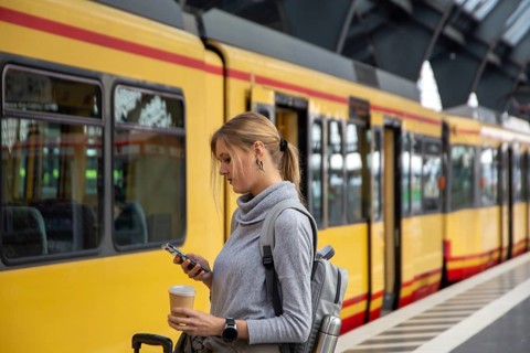 Close-up of a young woman in front of a train at the station