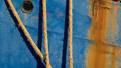 Detailed view of the side of a blue ship with ropes and rusty patches, Gythio, Mani, Peloponnese,