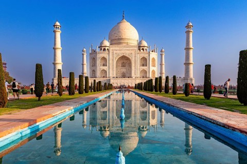 The sublime Taj Mahal is reflected in a long pool of water under a blue sky, Taj Mahal, Agra,