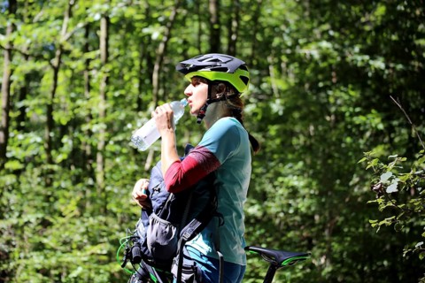 Symbolic image for drinking enough during sport: mountain biker quenches her thirst