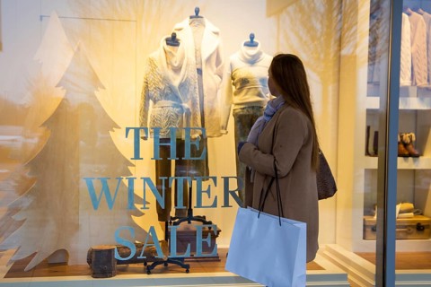 Symbolic image winter sale: Young woman standing in front of a shop window on which THE WINTER SALE