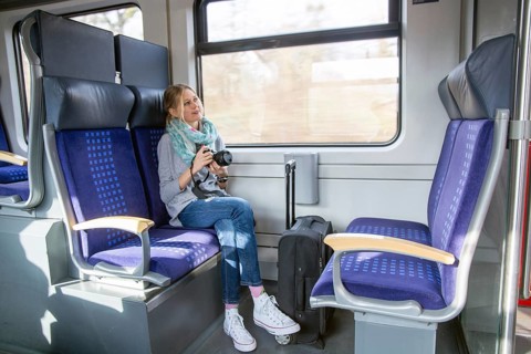 Young woman on a train holding a professional camera